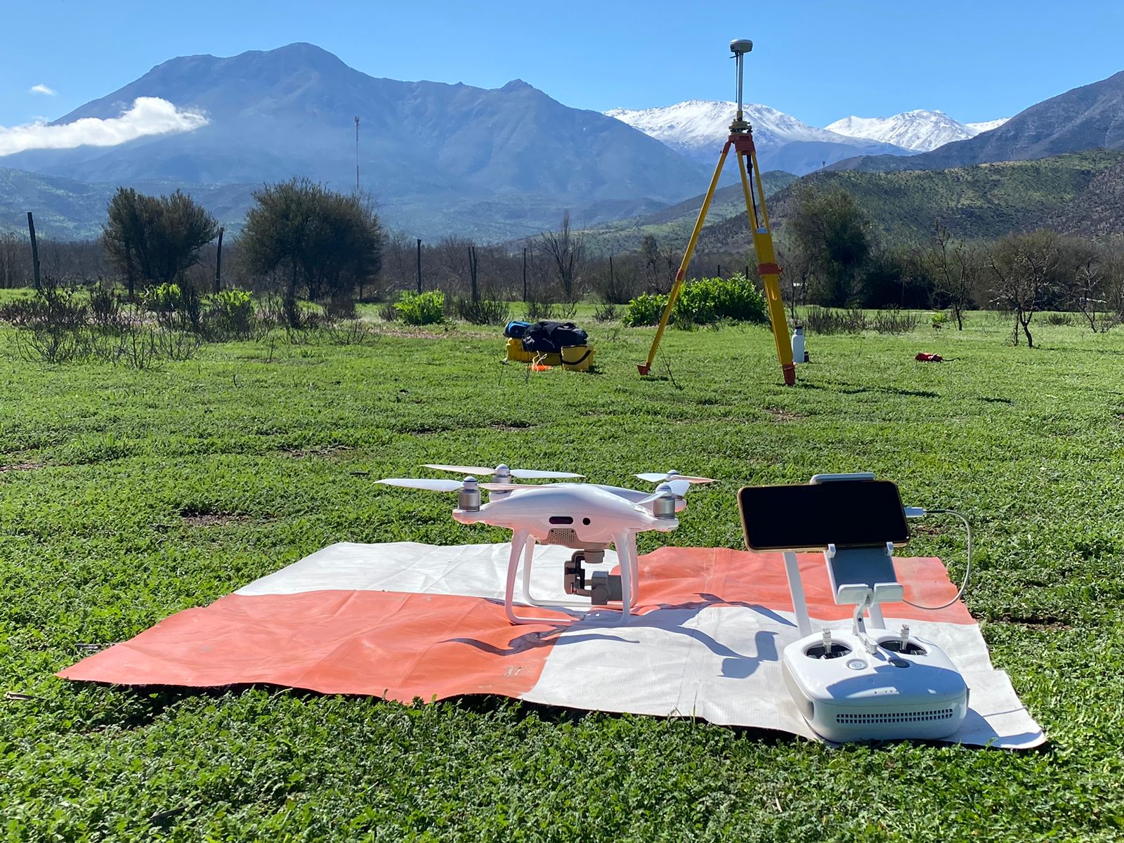 Dron, controlador y estación GNSS base en terreno con la cordillera nevada del Valle de Aconcagua al fondo